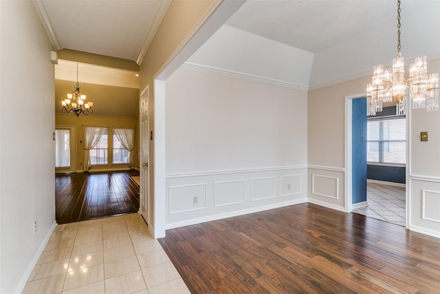 empty room featuring wood-type flooring, a wealth of natural light, and an inviting chandelier