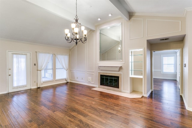 unfurnished living room featuring ornamental molding, hardwood / wood-style floors, a tile fireplace, and vaulted ceiling with beams