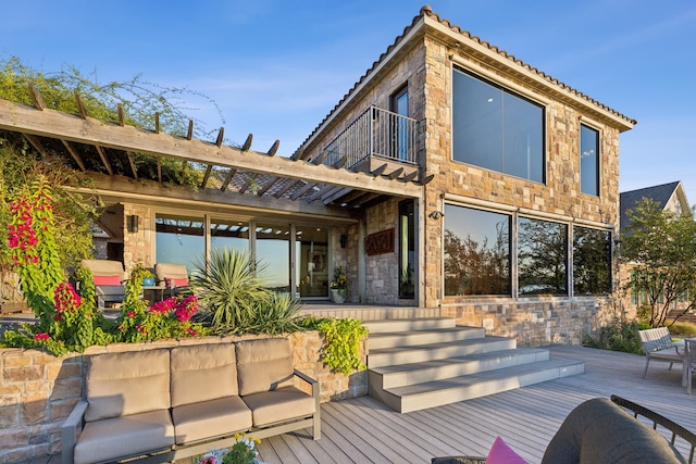 back of property with a balcony, outdoor lounge area, a deck, and a pergola