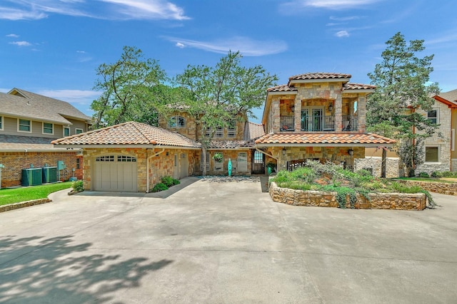 mediterranean / spanish home featuring a garage, a balcony, and central air condition unit