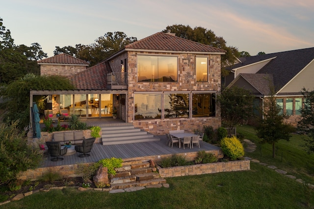 back house at dusk featuring a yard and a deck