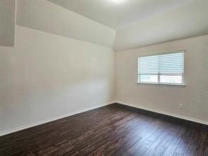 spare room featuring dark wood-type flooring and lofted ceiling