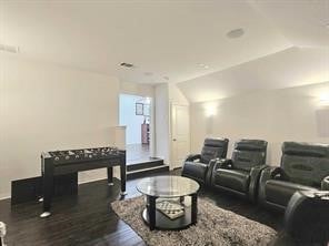 cinema room featuring dark wood-type flooring and vaulted ceiling