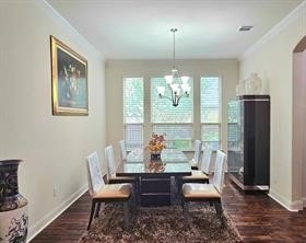 dining area featuring crown molding, dark wood-type flooring, and a chandelier