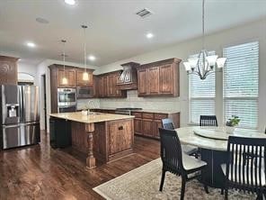 kitchen featuring pendant lighting, appliances with stainless steel finishes, dark hardwood / wood-style flooring, and an island with sink