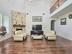 living room featuring dark wood-type flooring, a fireplace, and a towering ceiling