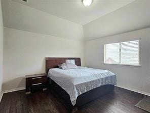 bedroom with dark wood-type flooring and vaulted ceiling