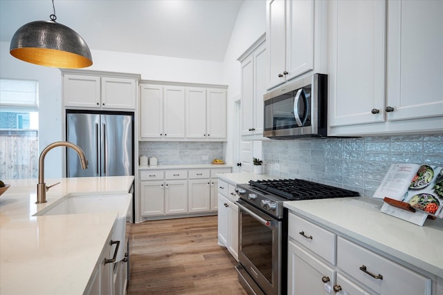 kitchen featuring stainless steel appliances, white cabinetry, sink, and pendant lighting