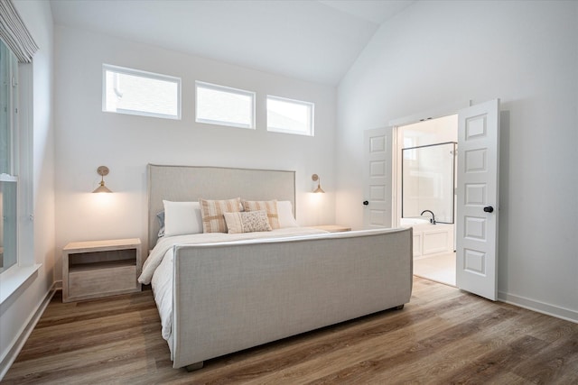 bedroom with hardwood / wood-style flooring, ensuite bathroom, lofted ceiling, and multiple windows