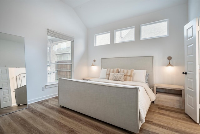 bedroom with multiple windows, vaulted ceiling, and hardwood / wood-style flooring