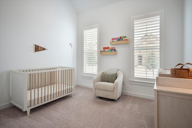 bedroom with lofted ceiling, a crib, and light colored carpet