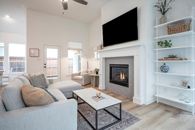 living room featuring a fireplace, ceiling fan, and light wood-type flooring