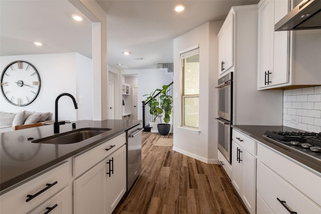 kitchen with dark wood-type flooring, sink, white cabinetry, appliances with stainless steel finishes, and exhaust hood