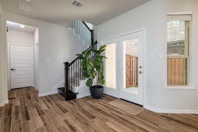 entrance foyer featuring wood tiled floor, stairs, visible vents, and baseboards