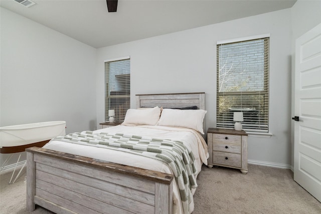 bedroom featuring light carpet, ceiling fan, visible vents, and baseboards