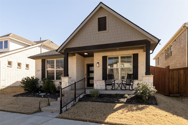 view of front of home featuring fence, a porch, and brick siding