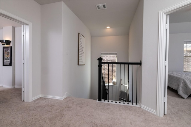 corridor with visible vents, carpet flooring, an upstairs landing, and a healthy amount of sunlight