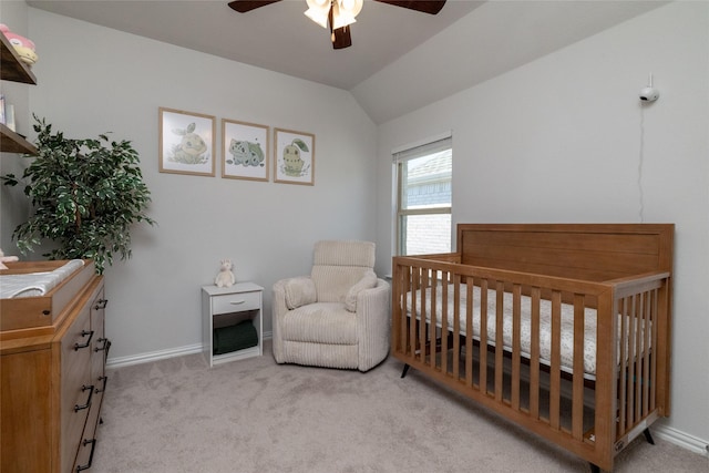 bedroom featuring a nursery area, ceiling fan, lofted ceiling, and light carpet