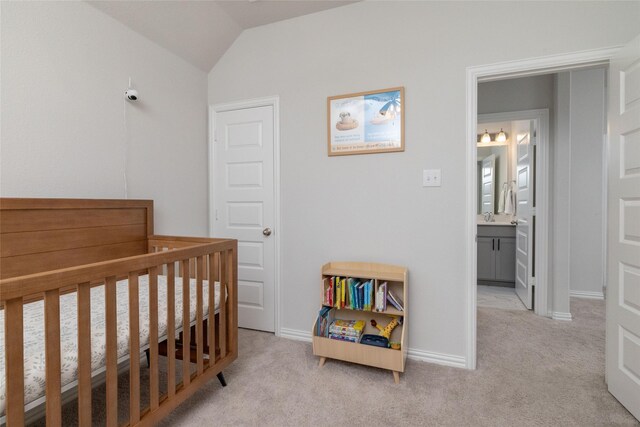 carpeted bedroom with vaulted ceiling, a nursery area, and sink