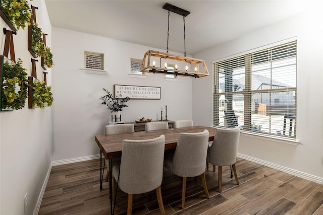 dining space with an inviting chandelier, baseboards, and wood finished floors