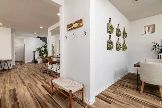 hallway with recessed lighting, stairway, baseboards, and wood finished floors