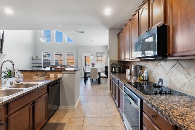 kitchen featuring decorative light fixtures, tasteful backsplash, sink, dark stone counters, and black appliances