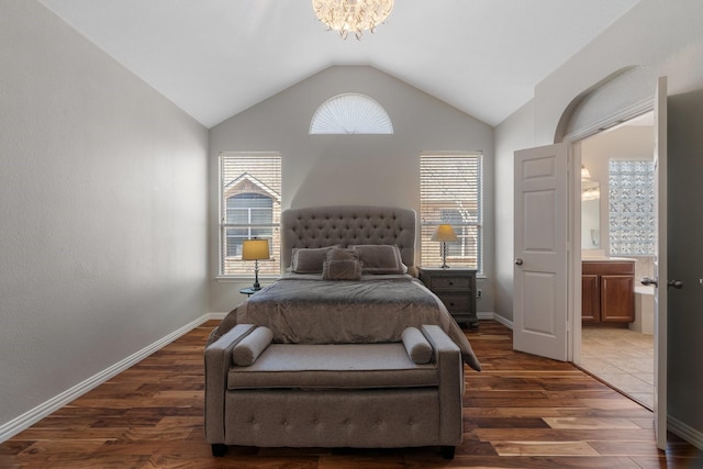 bedroom with dark wood-type flooring, ensuite bathroom, a chandelier, and vaulted ceiling