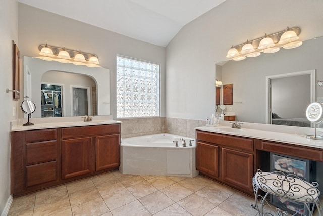 bathroom with lofted ceiling, vanity, tile patterned floors, and a tub to relax in