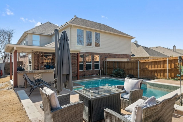 back of property featuring a fenced in pool, a patio area, and an outdoor fire pit