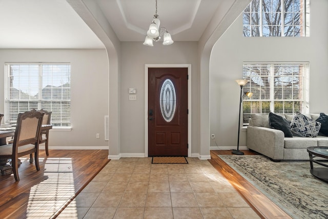 entryway featuring light hardwood / wood-style flooring, a chandelier, and a tray ceiling