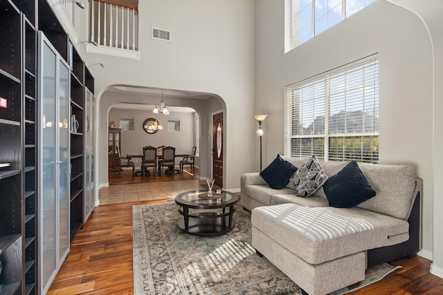 living room featuring dark wood-type flooring, a chandelier, and a high ceiling