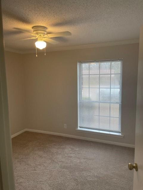 empty room with ornamental molding, light colored carpet, ceiling fan, and a textured ceiling