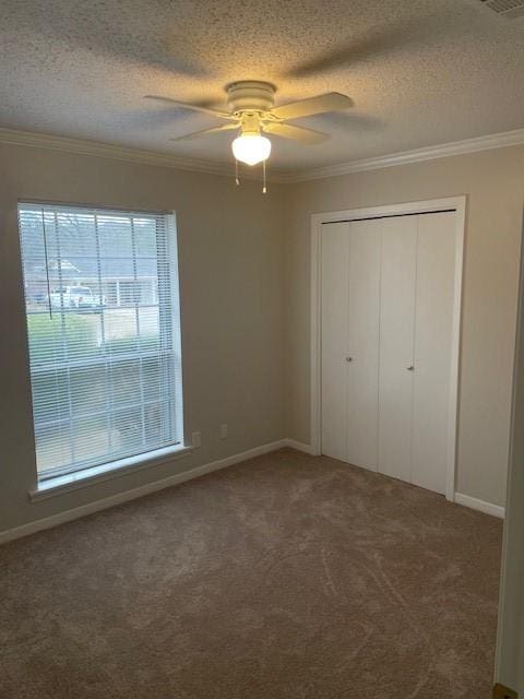 unfurnished bedroom with crown molding, dark carpet, multiple windows, and a textured ceiling