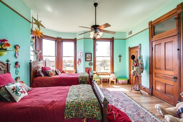 bedroom with ceiling fan, multiple windows, and light hardwood / wood-style flooring