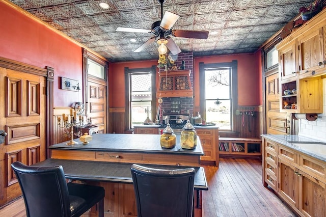 kitchen with ceiling fan, plenty of natural light, a kitchen bar, and light wood-type flooring