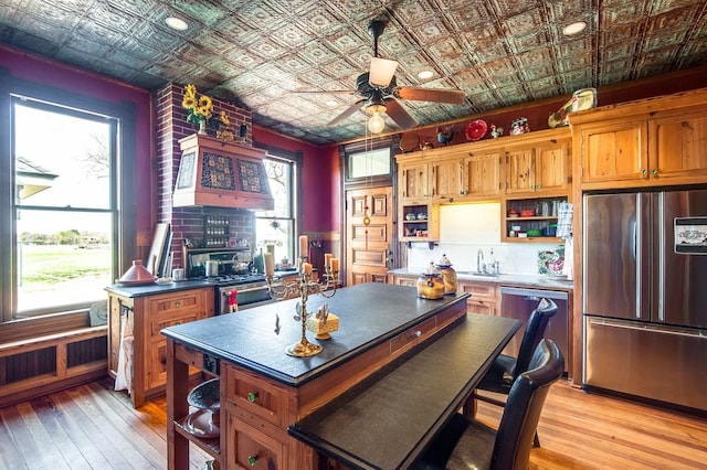 kitchen featuring stainless steel appliances, a center island, a wealth of natural light, and light hardwood / wood-style floors