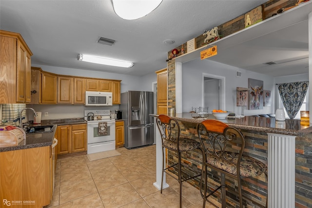 kitchen featuring sink, backsplash, a kitchen breakfast bar, light tile patterned floors, and white appliances