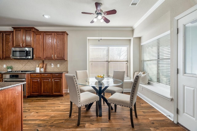 dining room with ceiling fan, crown molding, plenty of natural light, and dark wood-type flooring