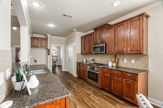 kitchen with stainless steel appliances, sink, dark wood-type flooring, and dark stone counters