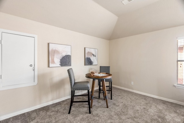 carpeted dining space featuring lofted ceiling