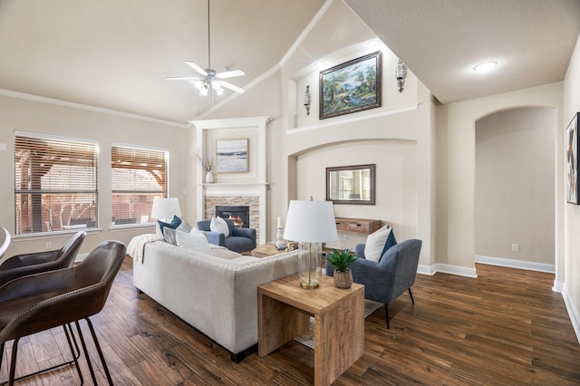 living room featuring dark wood-type flooring, ceiling fan, a fireplace, and crown molding