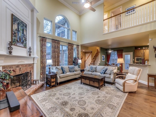 living room featuring a fireplace, a ceiling fan, wood finished floors, and ornamental molding