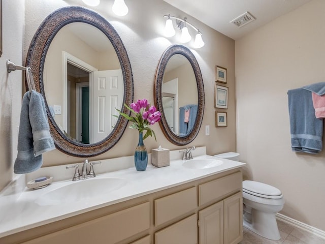 bathroom with toilet, double vanity, visible vents, and a sink