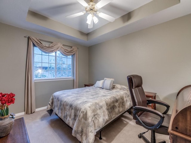 carpeted bedroom with ceiling fan and a tray ceiling