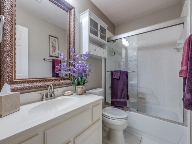 full bath featuring combined bath / shower with glass door, vanity, toilet, and tile patterned floors