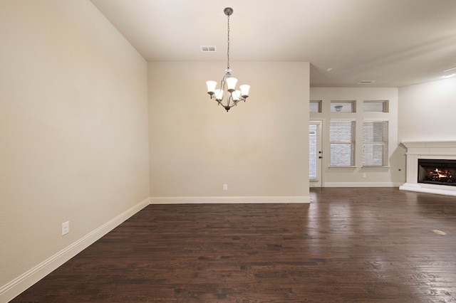 unfurnished living room with a notable chandelier and dark hardwood / wood-style flooring