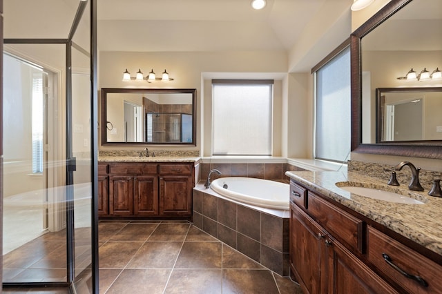 bathroom with tile patterned flooring, vanity, separate shower and tub, and vaulted ceiling