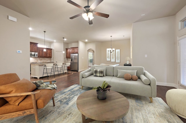 living room with dark hardwood / wood-style floors and ceiling fan with notable chandelier