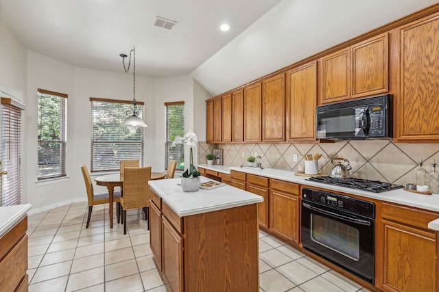 kitchen featuring decorative light fixtures, a wealth of natural light, black appliances, and a center island