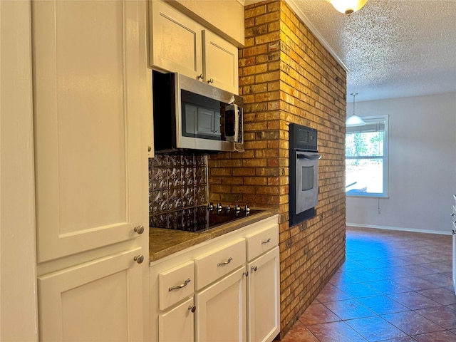 kitchen featuring white cabinets, tile patterned floors, stainless steel appliances, and a textured ceiling